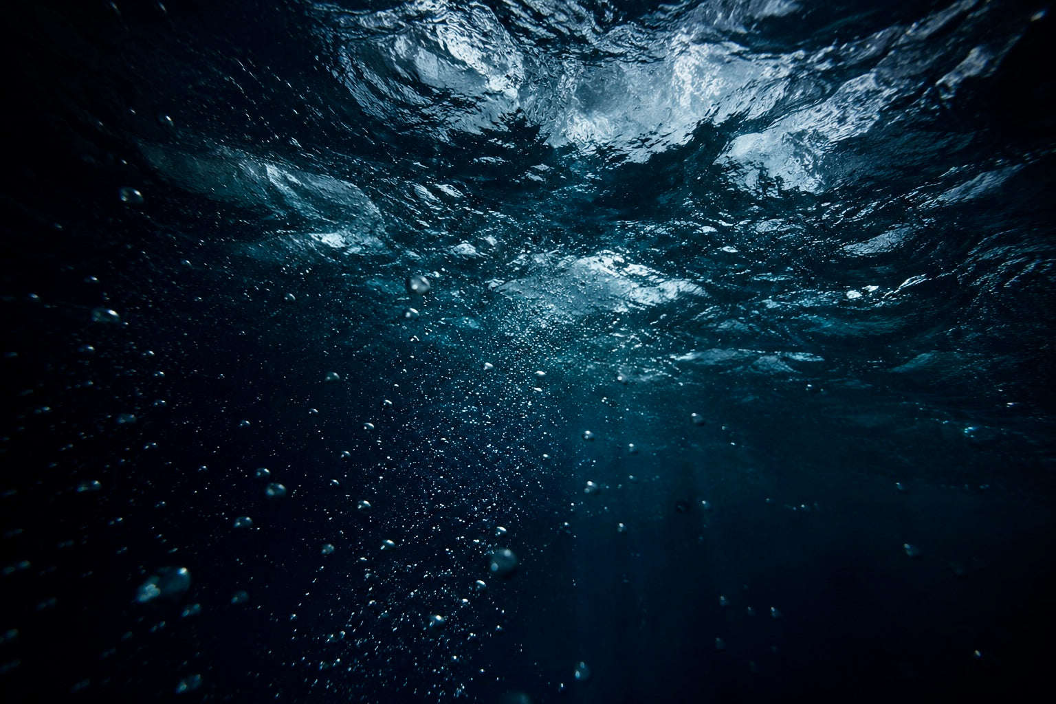 Underwater view with bubbles and light refraction in dark water
